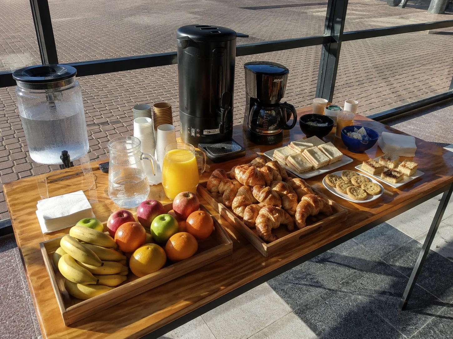 Mesa de catering con desayuno, frutas, medialunas y jugos